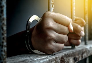 Prisoner with Hands Gripping Bars