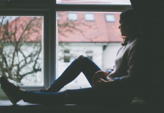 Woman Looking out a Window from Shadows