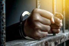 Prisoner with Hands Gripping Bars